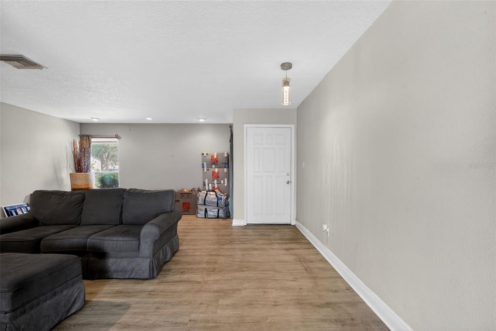 A living room features gray walls, wood-look flooring, a dark sectional sofa, and a white door — 2738 FIRESIDE COURT, ORLANDO, FL