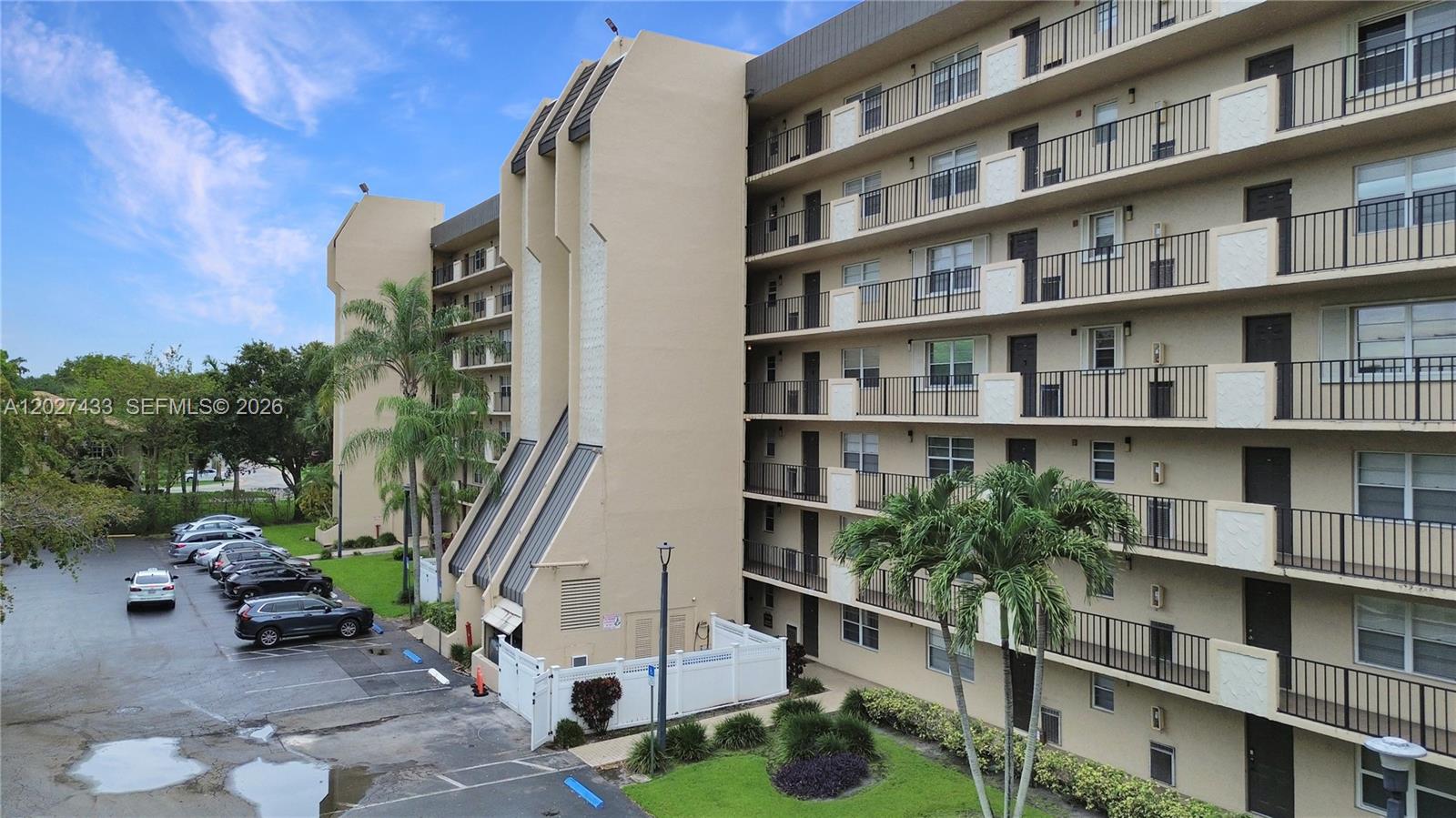 An exterior view shows a multi-story apartment building with balconies and an adjacent parking lot — 3300 W Rolling Hills Cir # 509, Davie FL 33328, DAVIE, FL