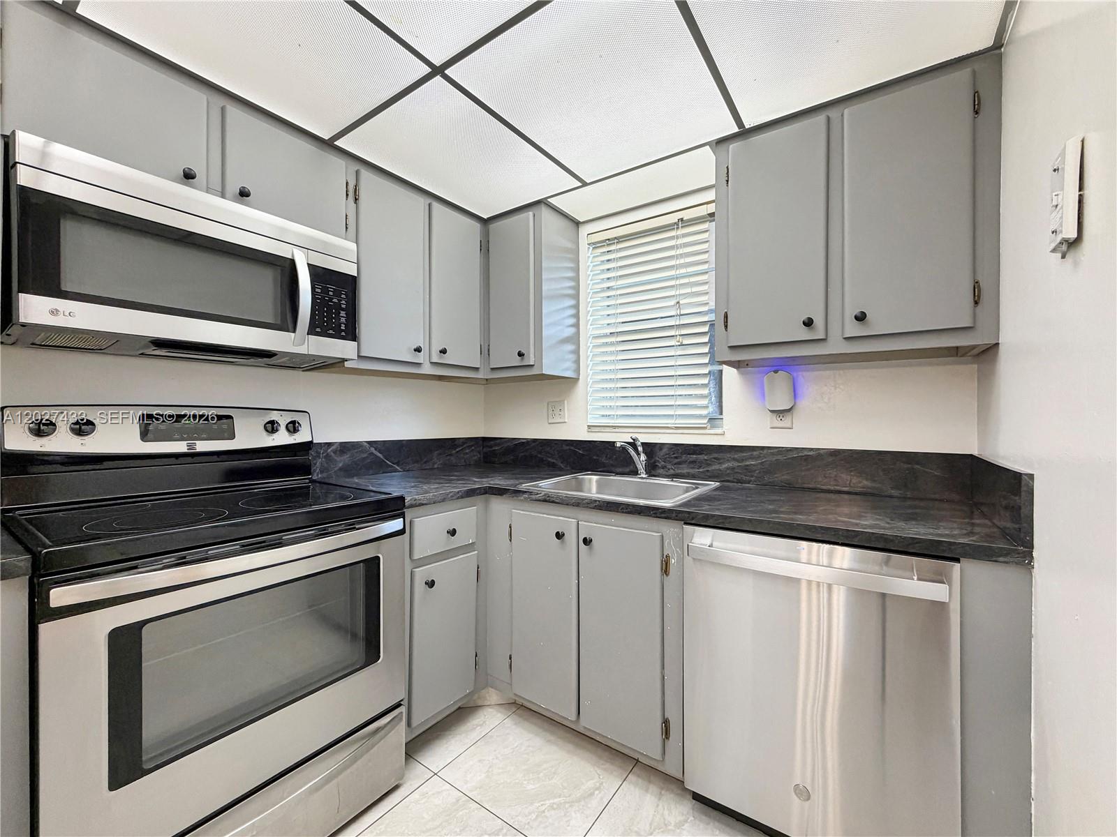 A kitchen features gray cabinets, stainless steel appliances, and dark countertops — 3300 W Rolling Hills Cir # 509, Davie FL 33328, DAVIE, FL