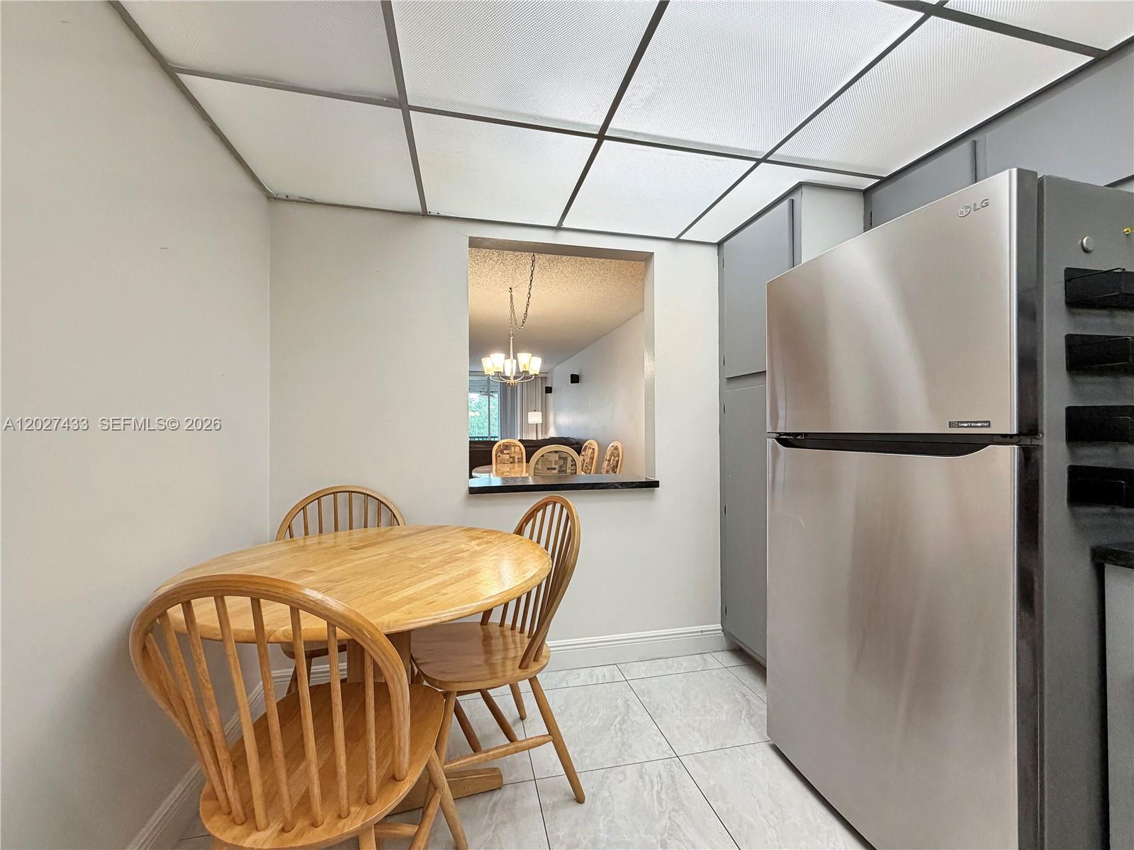 A kitchen features a round wooden table, a stainless steel refrigerator, and a drop ceiling — 3300 W Rolling Hills Cir # 509, Davie FL 33328, DAVIE, FL
