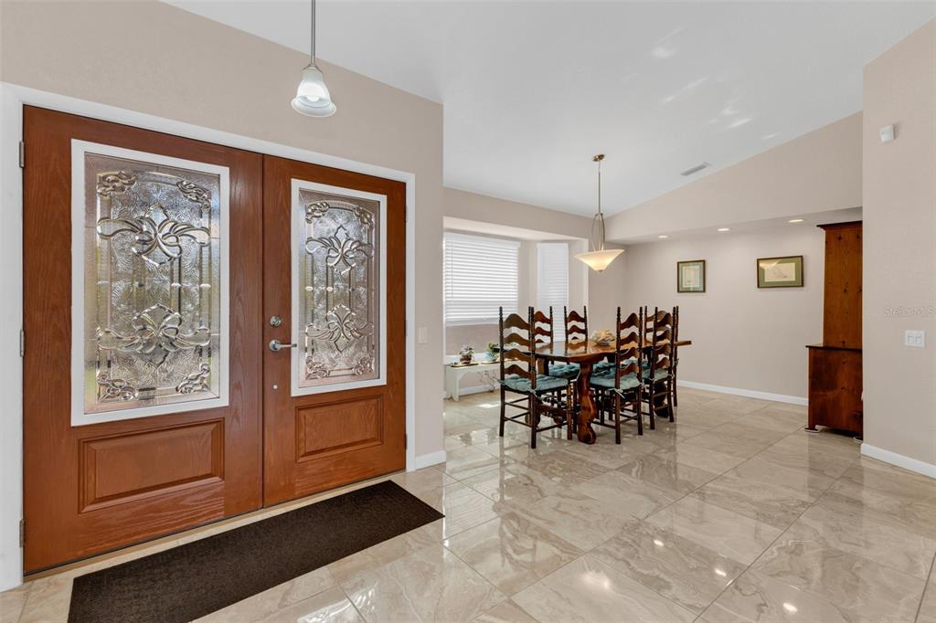 An entryway with double wood doors leads into a dining room with tiled floors — 29350 SAM WAY, PUNTA GORDA, FL