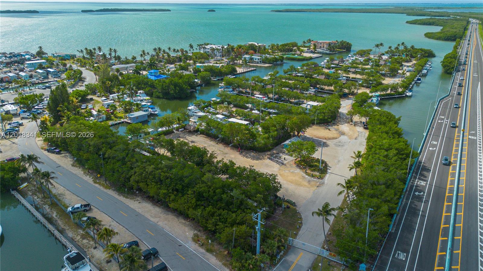 An aerial view shows a coastal property with boat slips, dense trees, and a highway — 100 Morr Ln C13, Key Largo FL 33037, KEY LARGO, FL