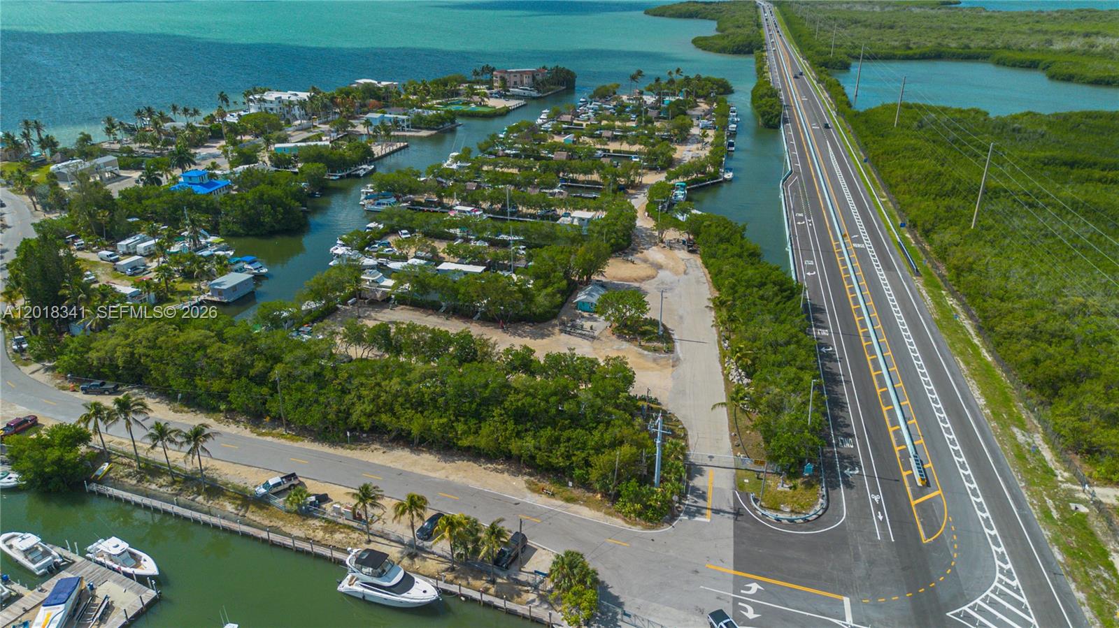 An aerial view shows a coastal property with boat slips, a road, and a bridge — 100 Morr Ln C13, Key Largo FL 33037, KEY LARGO, FL