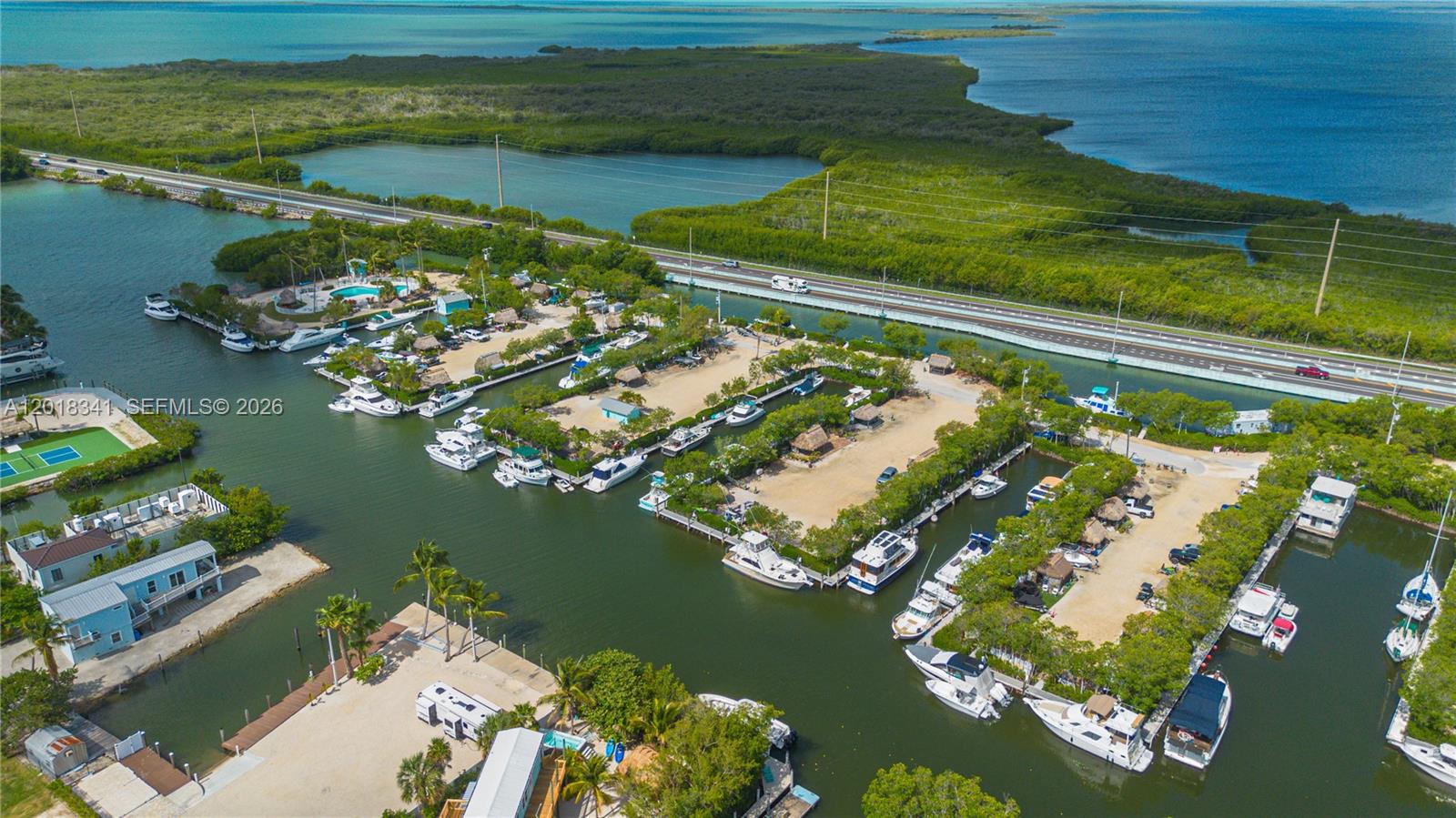 An aerial view shows a marina with numerous docked boats, sandy lots, and a highway — 100 Morr Ln C13, Key Largo FL 33037, KEY LARGO, FL