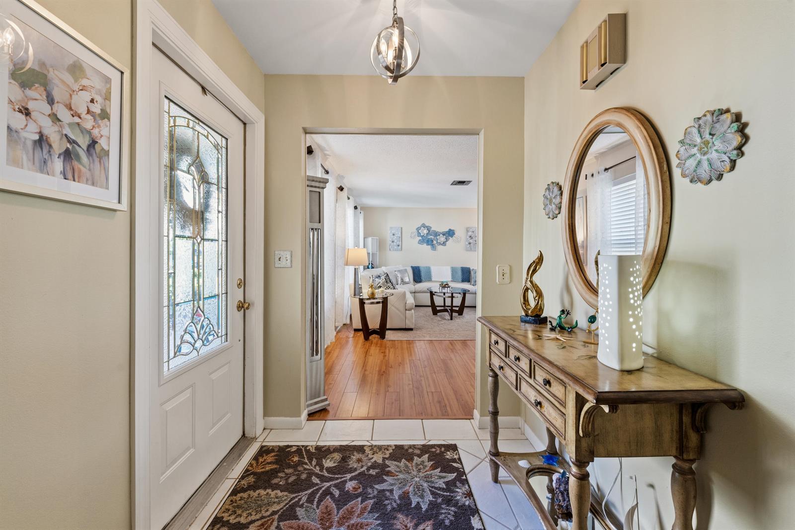 An entryway features a white front door, a wooden console table, and a view into a living room — 4176 SE Fairway Court, Stuart FL 34997, STUART, FL