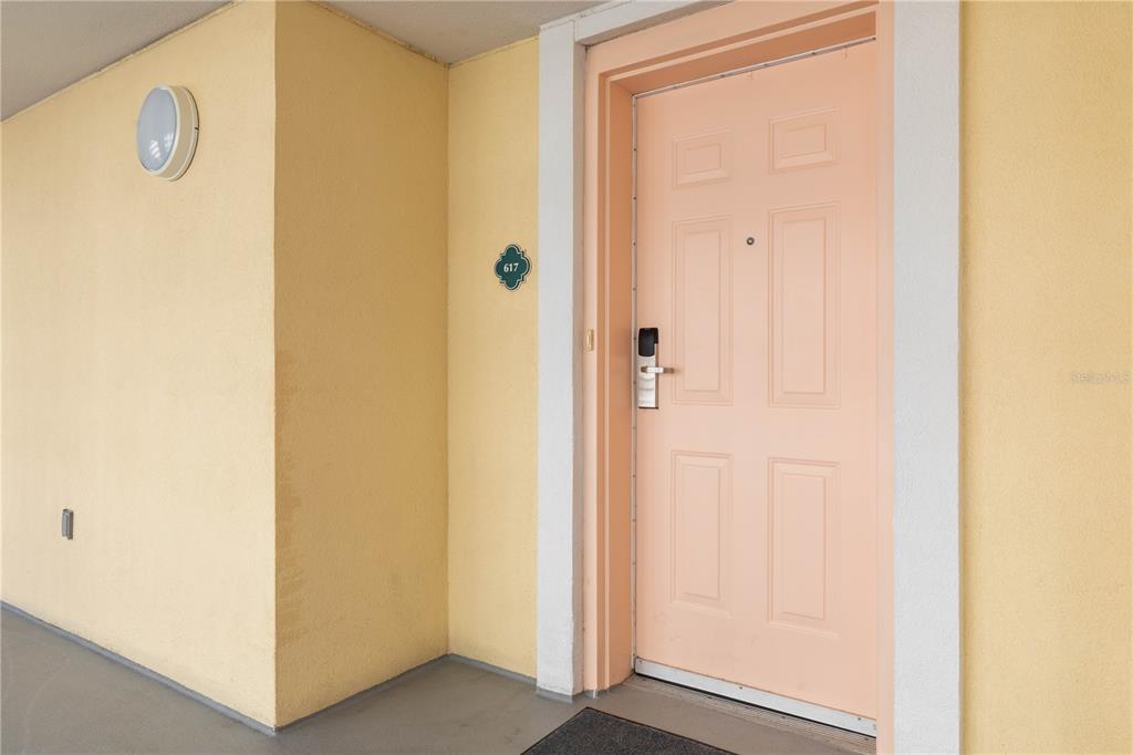 A peach-colored door with a digital lock is set into a yellow exterior wall — 200 OCEAN CREST DRIVE UNIT 617, PALM COAST, FL