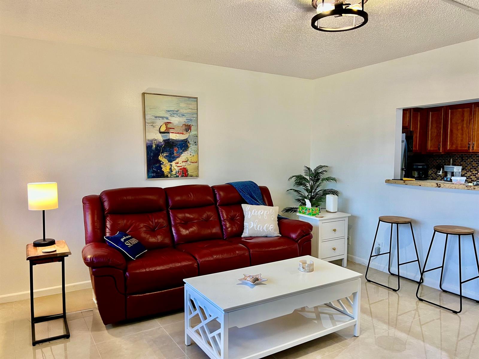 A living room features a red leather sofa, white coffee table, and a kitchen pass-through — 1011 Harwood C # 1011, Deerfield Beach FL 33442, DEERFIELD BEACH, FL