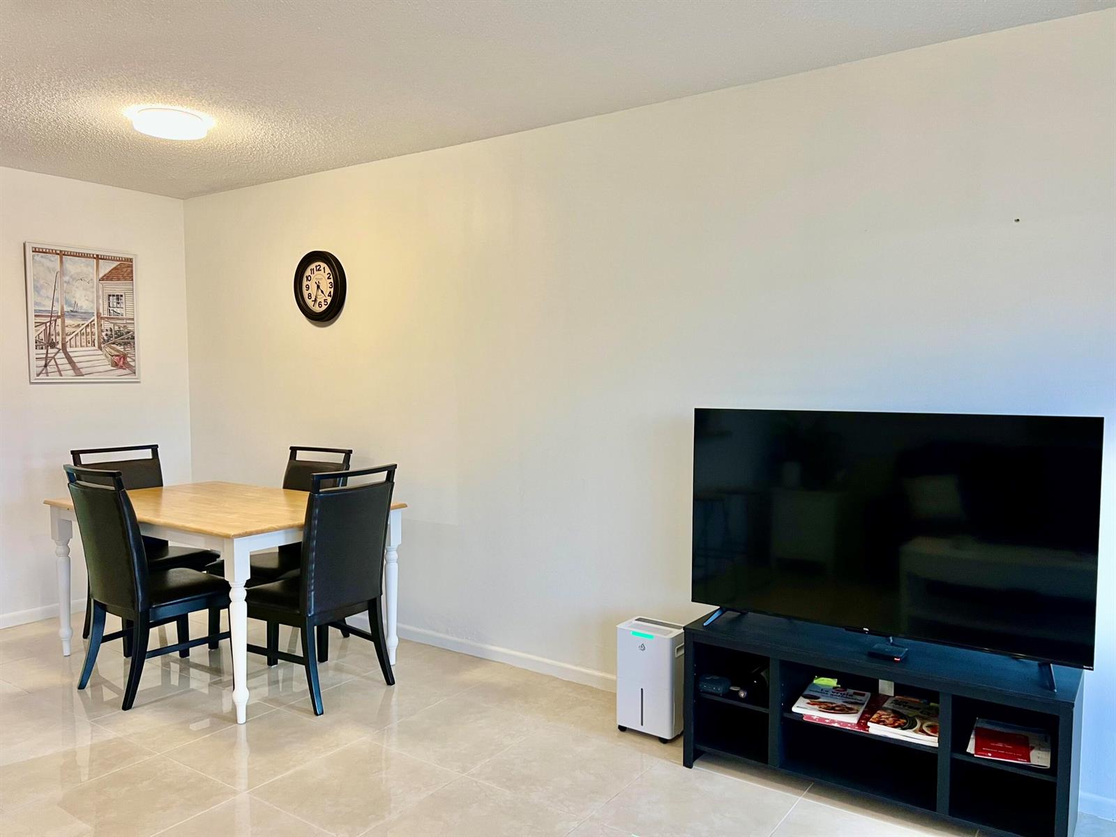 A dining area and living room space with a television, dining set, and tiled floors — 1011 Harwood C # 1011, Deerfield Beach FL 33442, DEERFIELD BEACH, FL