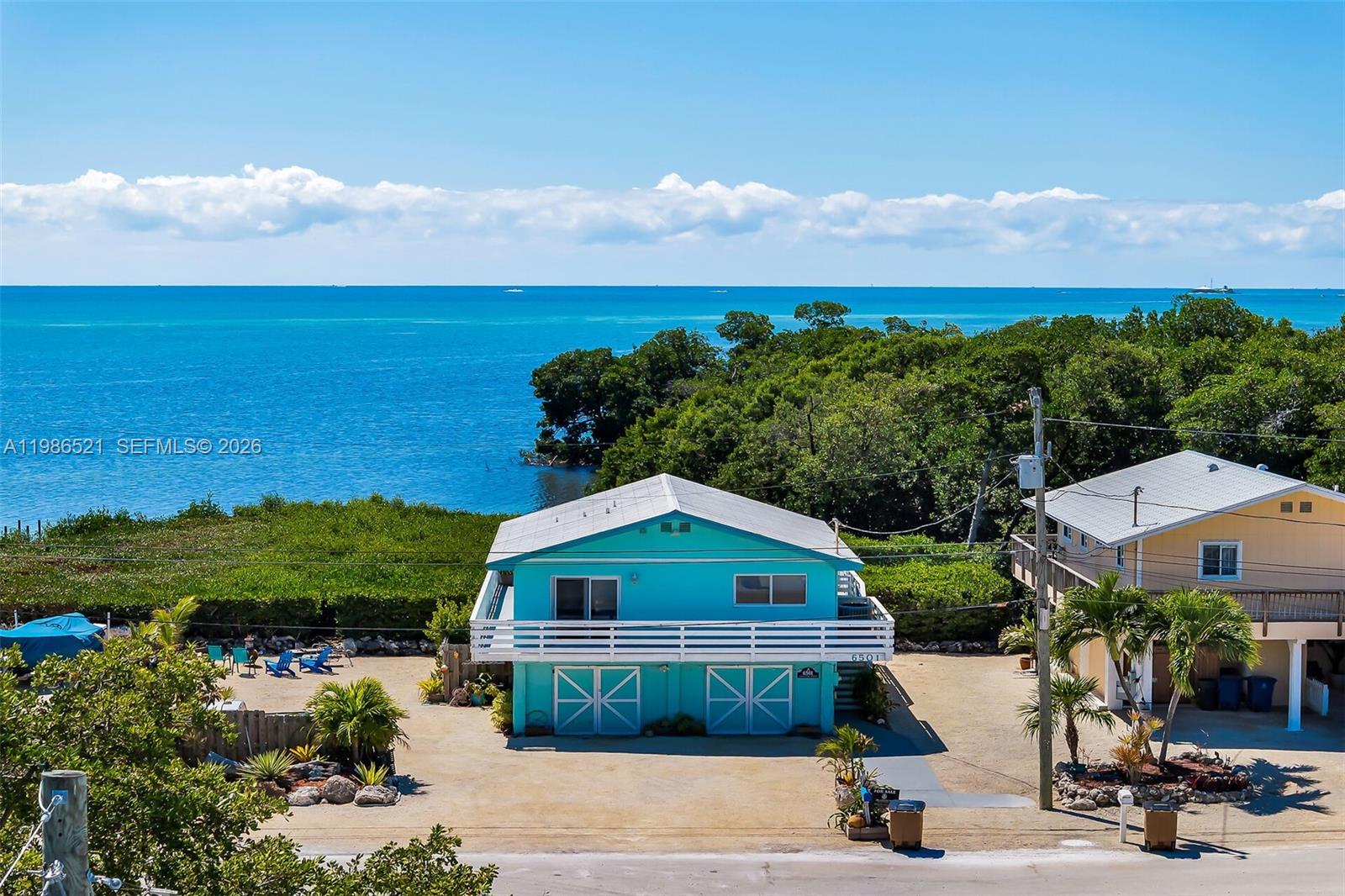 A turquoise two-story house with a white balcony sits near the ocean and trees — 6501 Oceanview Ave, Marathon FL 33050, MARATHON, FL