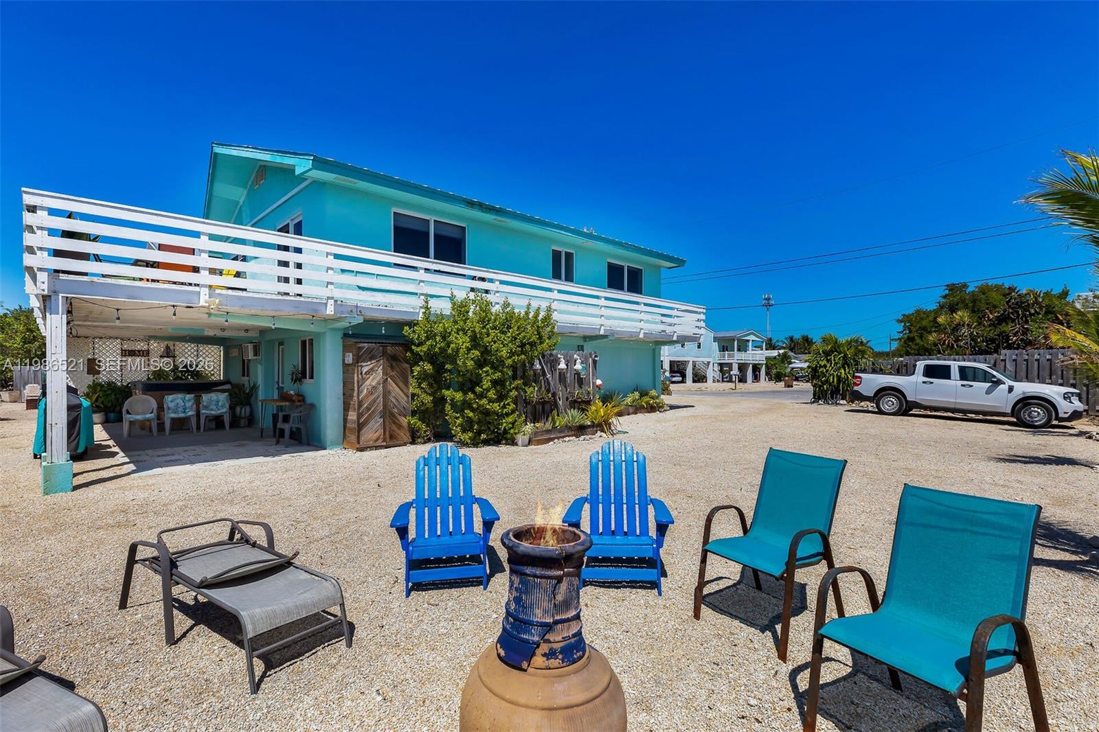 A turquoise two-story house features a white balcony and a gravel yard with chairs — 6501 Oceanview Ave, Marathon FL 33050, MARATHON, FL