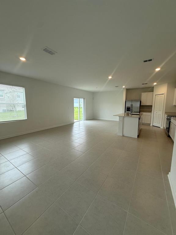 An open-concept living area features light-colored tile flooring, a kitchen island, and sliding glass doors — 3634 HARDMAN DRIVE, LAKE WALES, FL