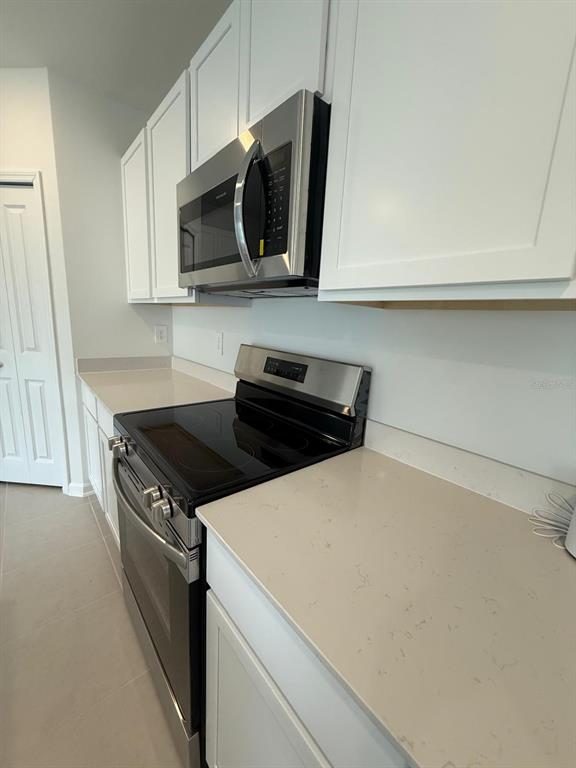 A kitchen features white cabinets, stainless steel appliances, and light-colored quartz countertops — 3634 HARDMAN DRIVE, LAKE WALES, FL
