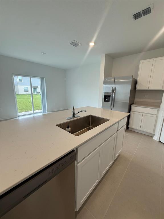 A kitchen island with a stainless steel sink sits before a refrigerator and white cabinets — 3634 HARDMAN DRIVE, LAKE WALES, FL