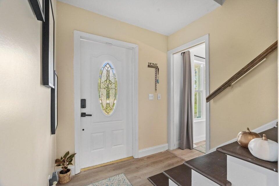 An entryway features a white front door with a glass insert, stairs, and light flooring — 301 20th Avenue SW, Vero Beach FL 32962, VERO BEACH, FL