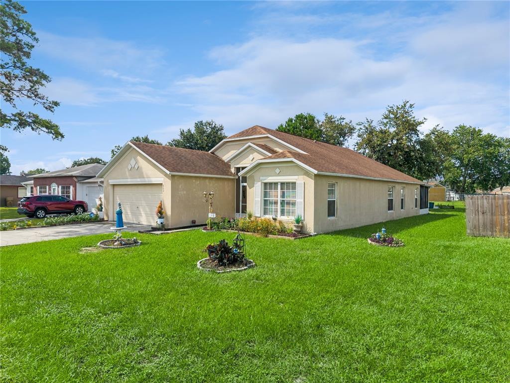 A single-story tan stucco house with a brown roof and a two-car garage — 663 MESILLA DRIVE, KISSIMMEE, FL