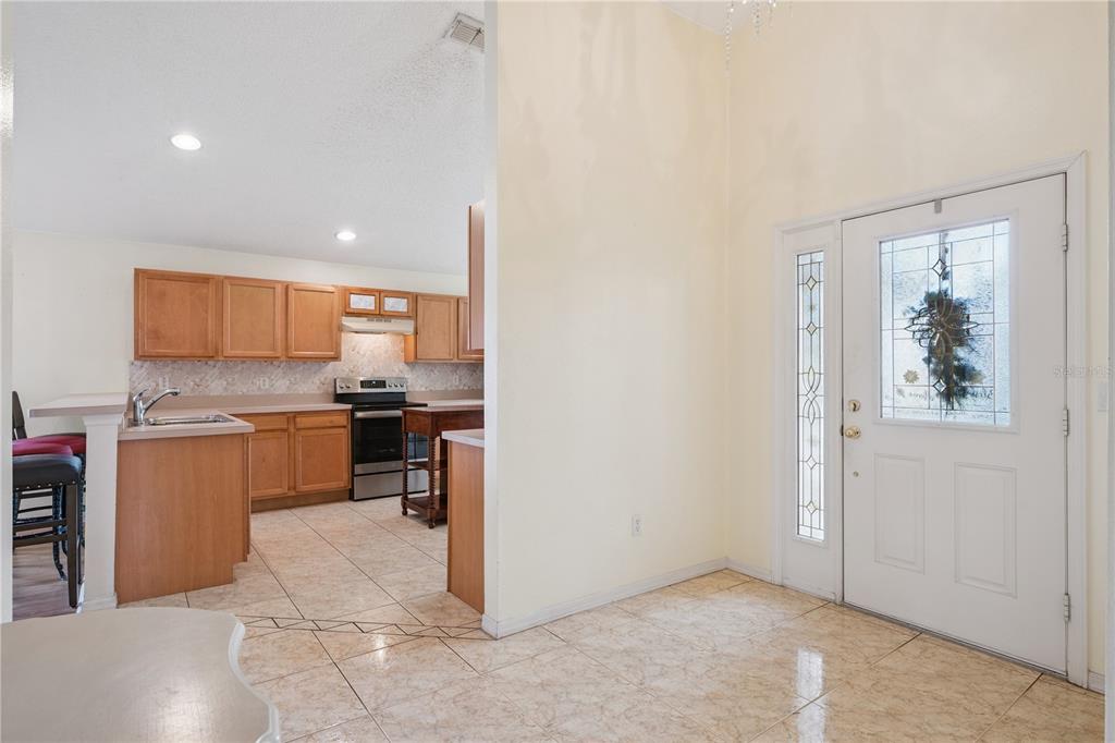 A tiled entryway leads into a kitchen with wooden cabinets and stainless steel appliances — 663 MESILLA DRIVE, KISSIMMEE, FL