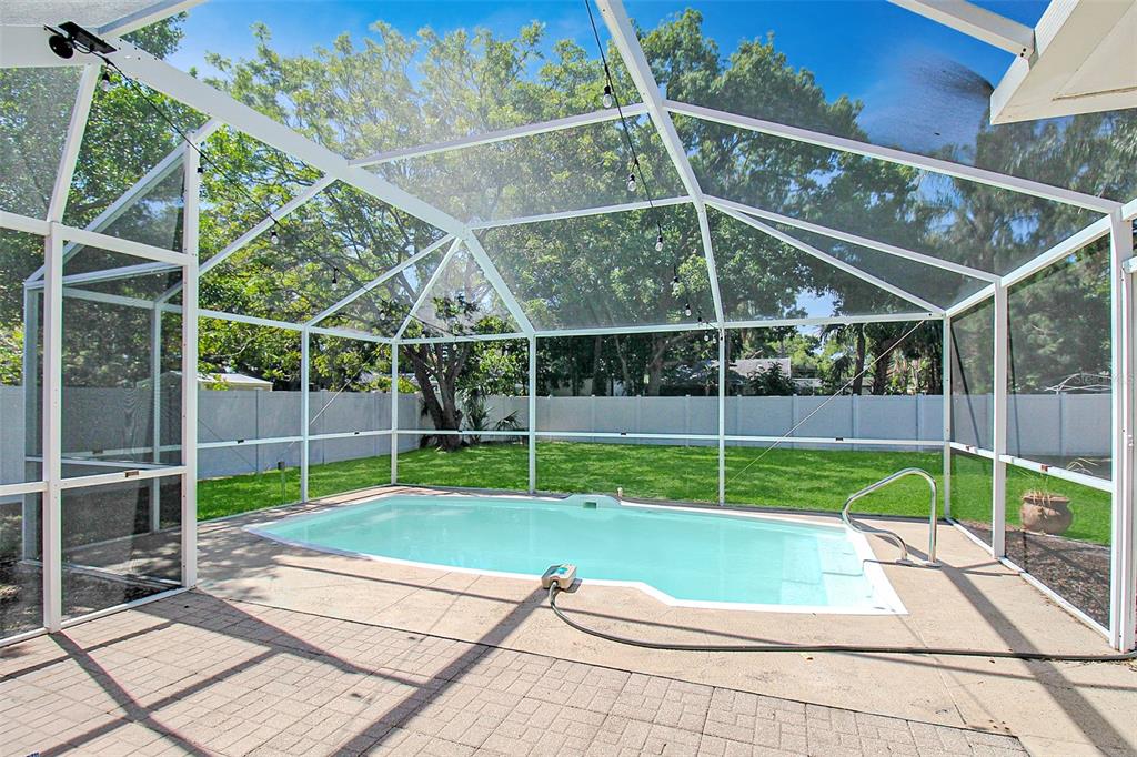 A rectangular swimming pool sits inside a screened-in patio enclosure with a paved deck — 2403 19TH AVENUE W, BRADENTON, FL