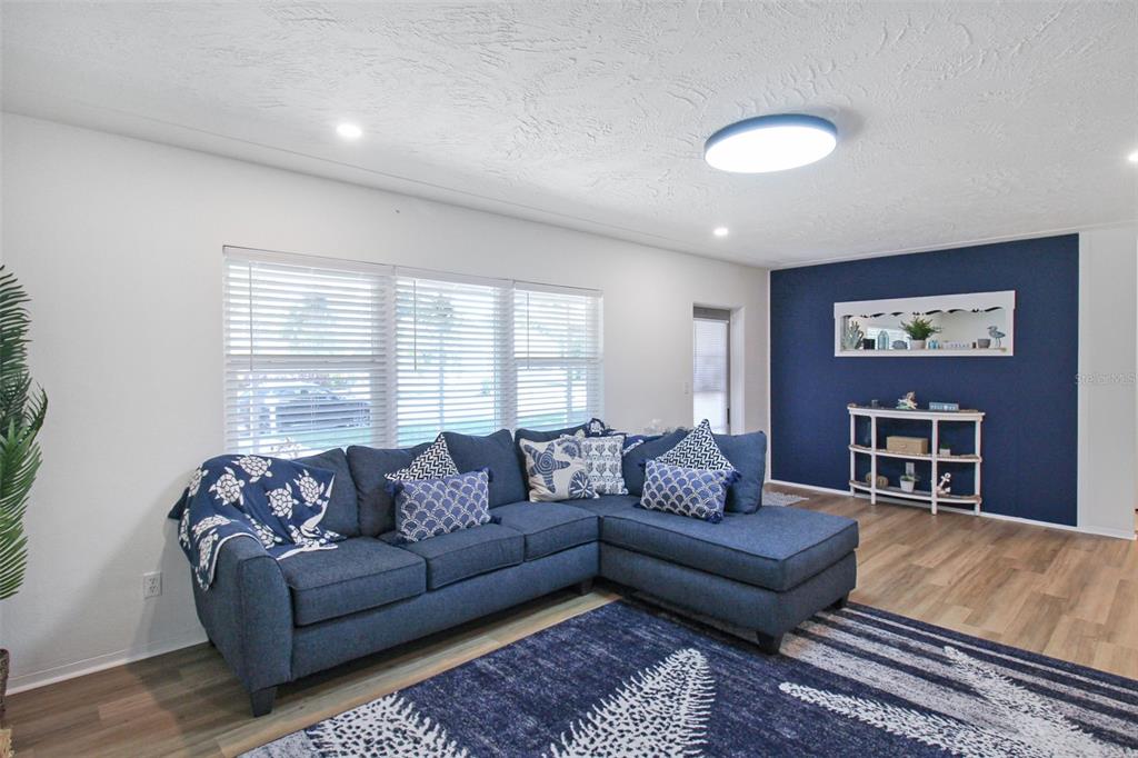 A living room features a blue sectional sofa, a patterned rug, and a navy accent wall — 2403 19TH AVENUE W, BRADENTON, FL