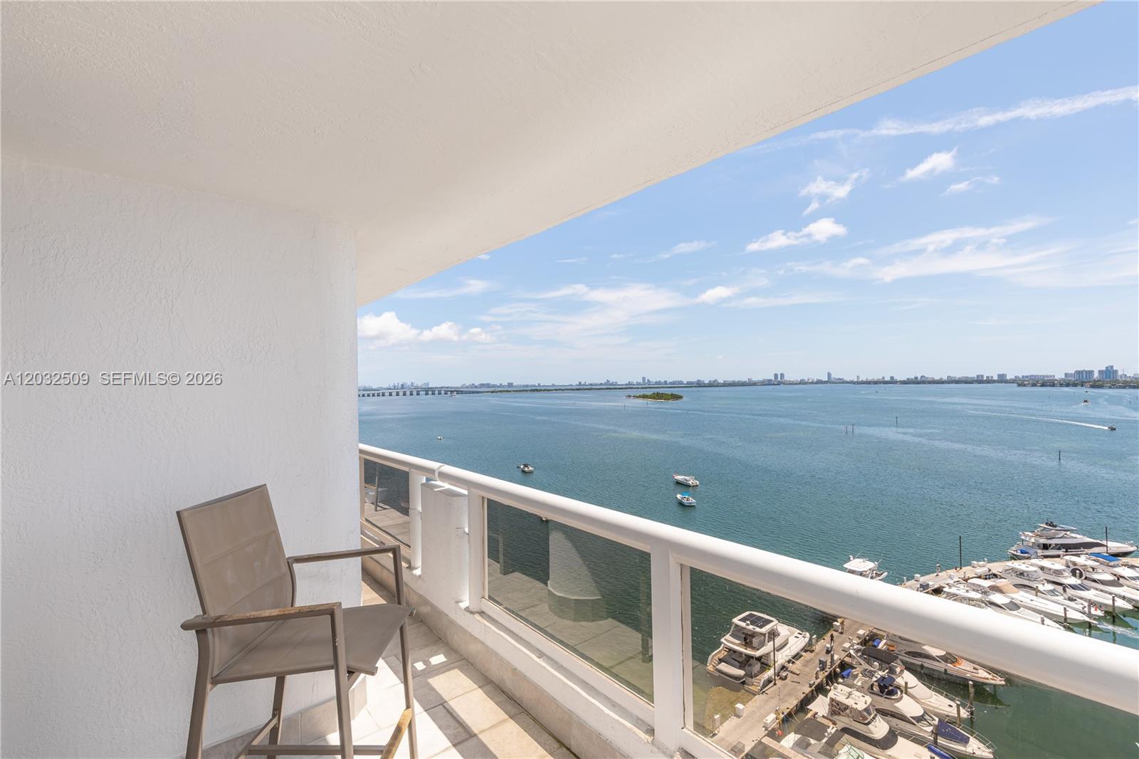 A balcony with a chair overlooks a marina and a large body of water — 1717 N Bayshore Dr # 1533, Miami FL 33132, MIAMI, FL