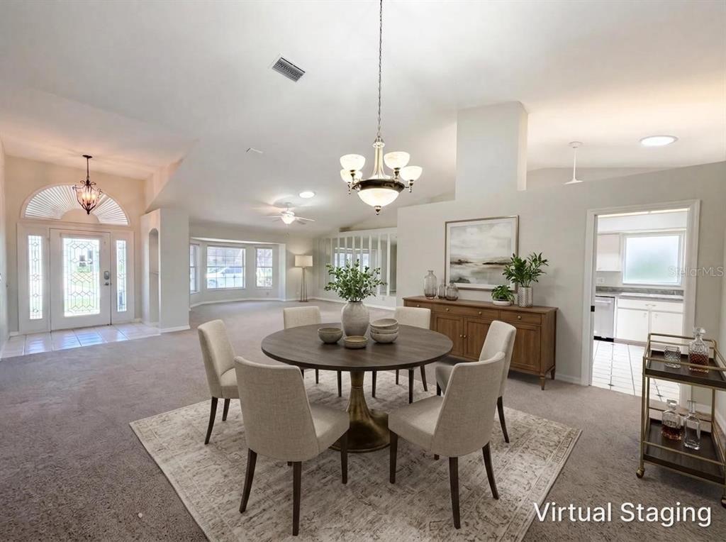 A dining area with a round table and chairs sits in an open-concept living space — 27305 RACQUET CIRCLE, LEESBURG, FL