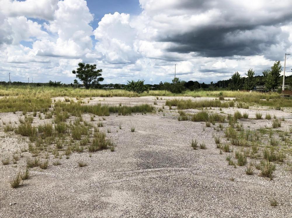 A large, flat, gravel-covered lot with patches of grass under a cloudy sky — 1801 STATE ROAD 559, POLK CITY, FL