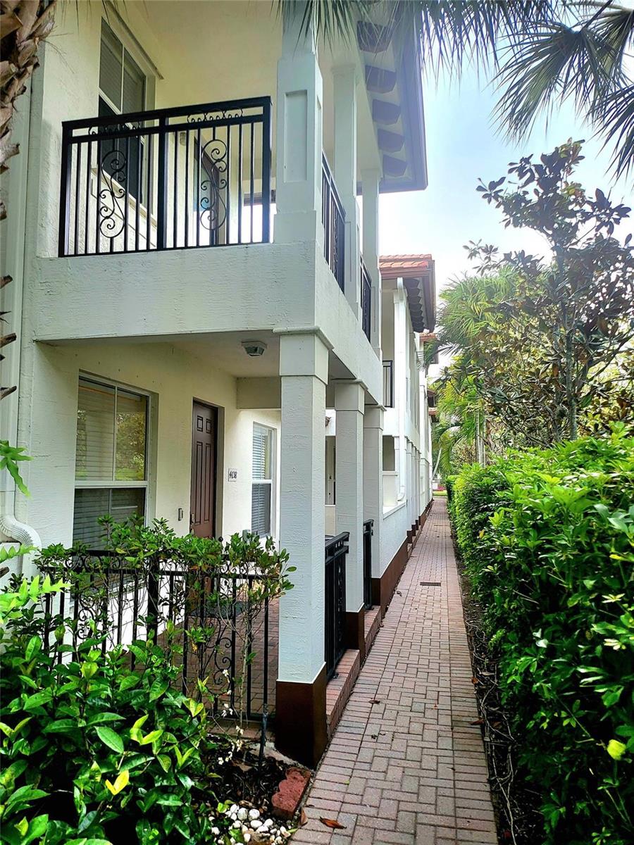 A two-story building exterior features a brick walkway, a ground-level patio, and an upper balcony — 4658 Monarch Way, Coconut Creek FL 33073, COCONUT CREEK, FL