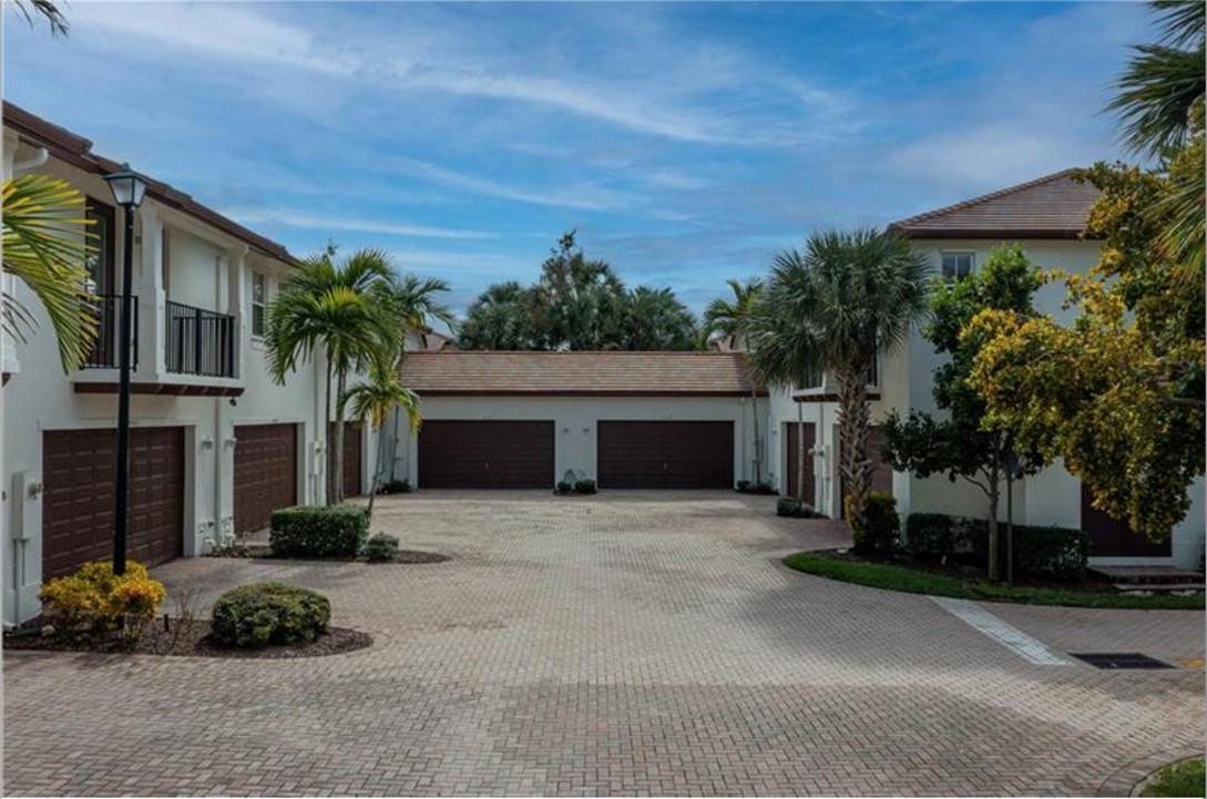 A paved courtyard features multiple garage doors and palm trees between two-story residential buildings — 4658 Monarch Way, Coconut Creek FL 33073, COCONUT CREEK, FL