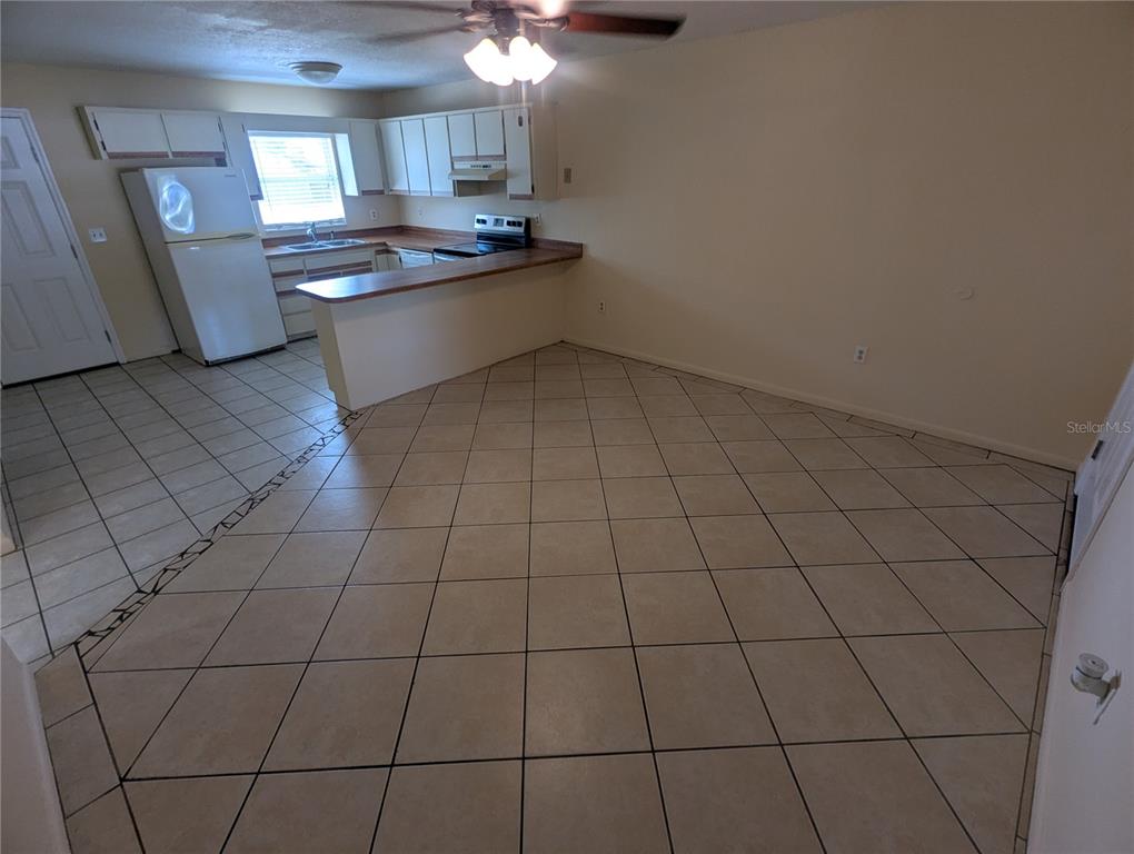An open-concept kitchen and dining area features white cabinets, tile flooring, and a breakfast bar — 824 N SAINT CLAIR ABRAMS AVENUE, TAVARES, FL
