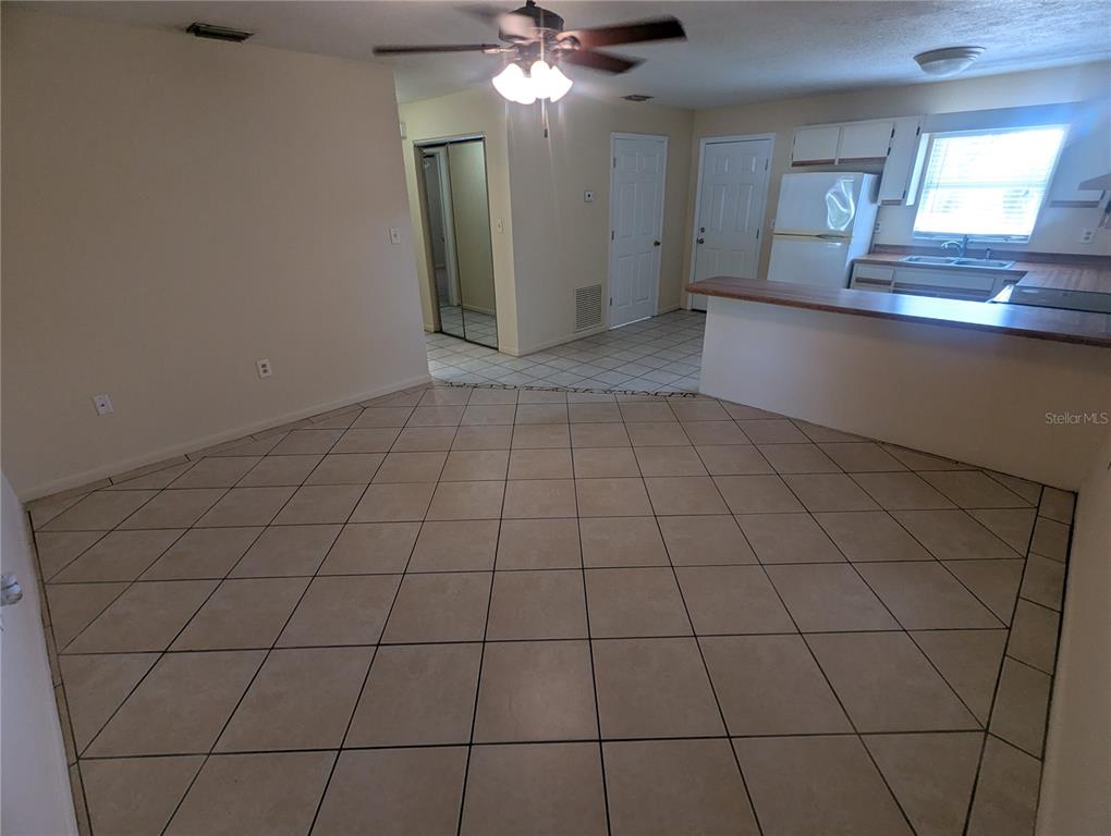 A tiled dining area leads to a kitchen with white cabinets and a breakfast bar — 824 N SAINT CLAIR ABRAMS AVENUE, TAVARES, FL