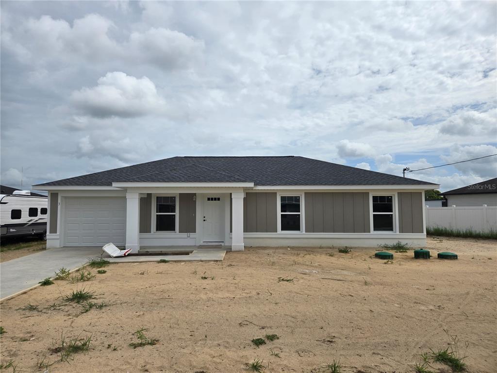 A single-story house with gray vertical siding, a dark shingled roof, and a concrete driveway — 3 WALNUT RUN COURT, OCALA, FL