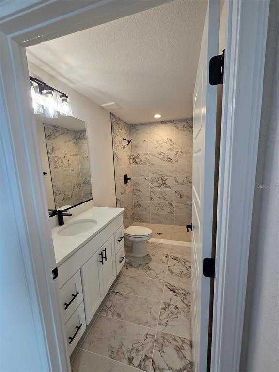 A bathroom features a white vanity, marble-look tile flooring, and a walk-in tiled shower — 3 WALNUT RUN COURT, OCALA, FL
