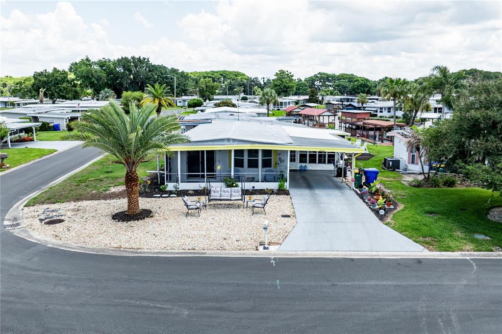 A single-story mobile home features a screened-in porch, a carport, and a landscaped front yard — 1004 TODD WAY, TAVARES, FL