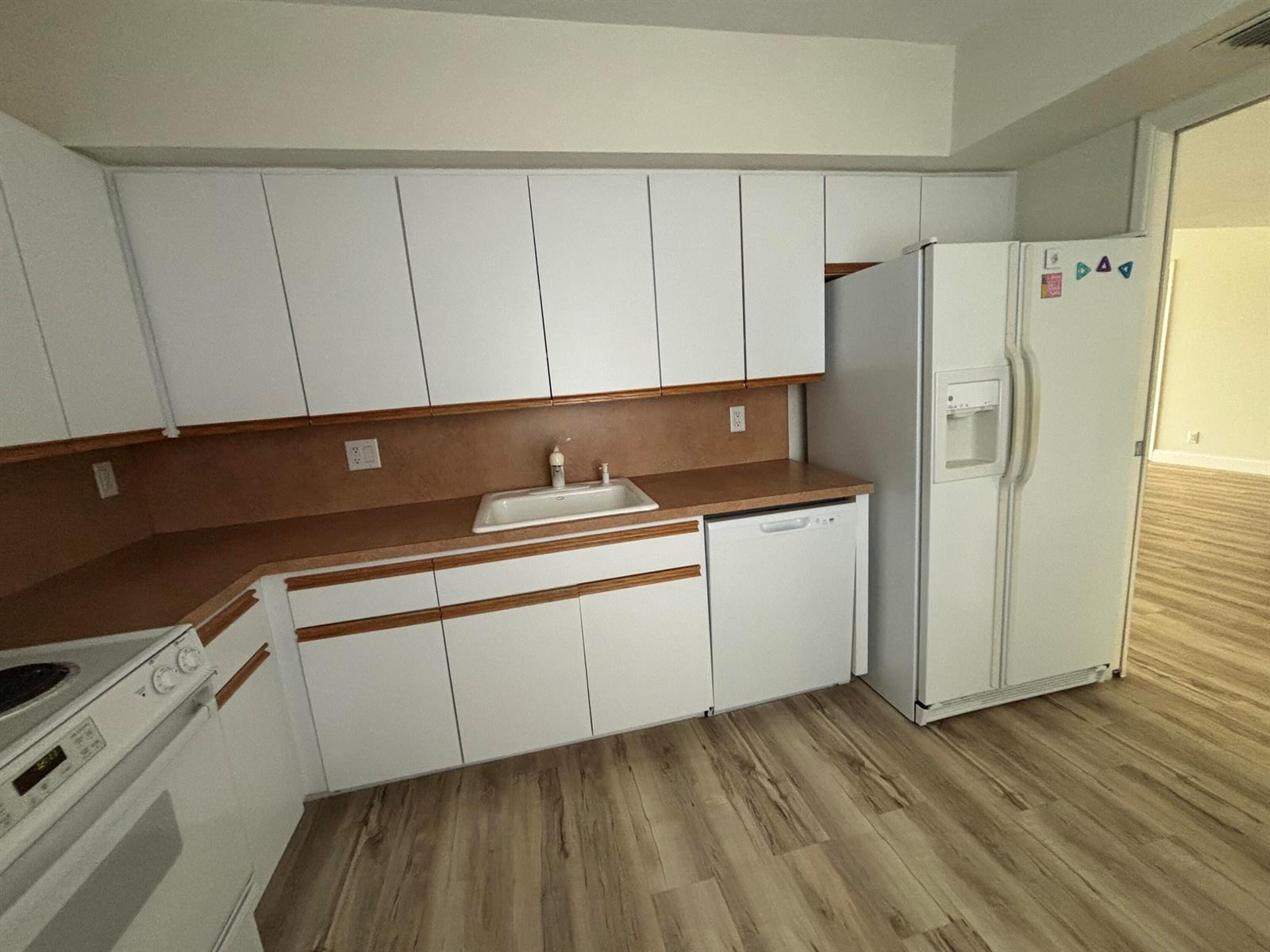 A kitchen features white cabinets, a brown countertop, a white sink, and white appliances — 555 Oaks Lane # 309, Pompano Beach FL 33069, POMPANO BEACH, FL