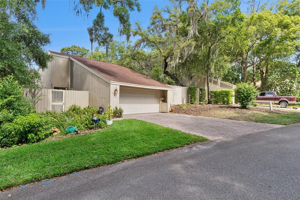 A tan, single-story house with a slanted roof, a garage, and a paved driveway — 106 HIDDEN OAK DRIVE, LONGWOOD, FL