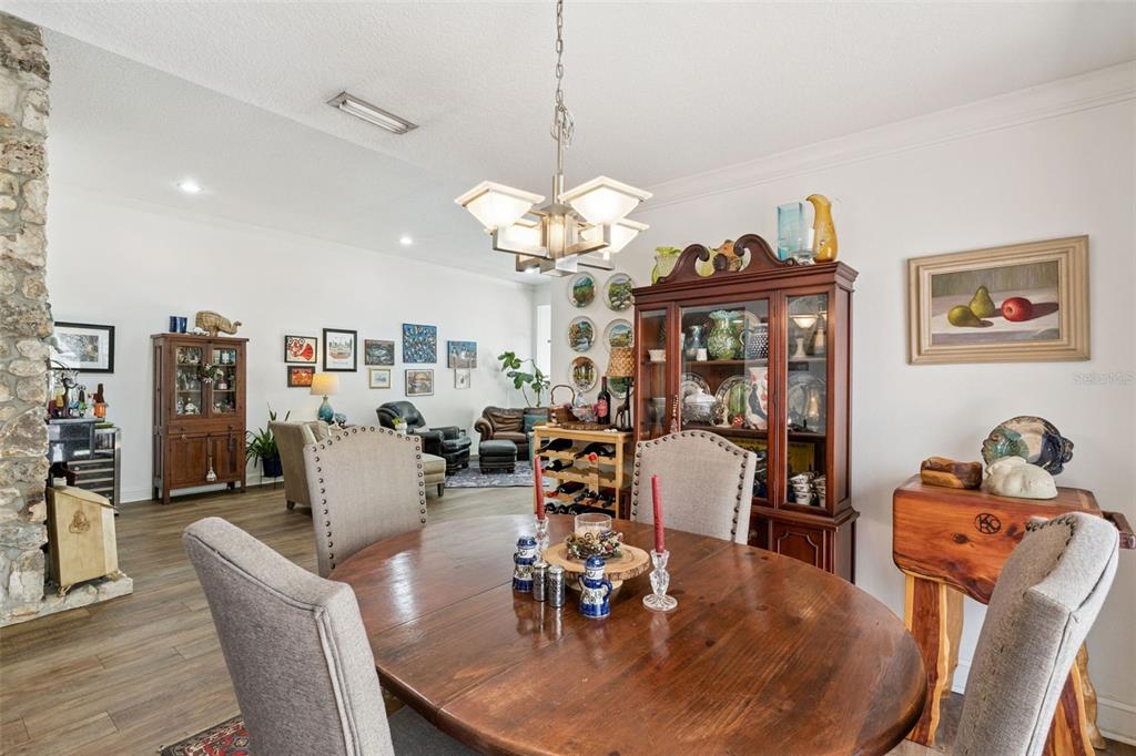 A dining room with a round wooden table, upholstered chairs, and a large china cabinet — 106 HIDDEN OAK DRIVE, LONGWOOD, FL