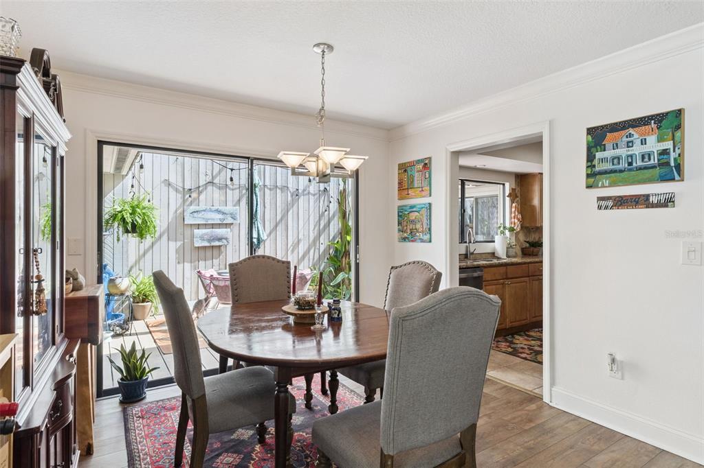 A dining room features a round wooden table, upholstered chairs, and a sliding glass door — 106 HIDDEN OAK DRIVE, LONGWOOD, FL