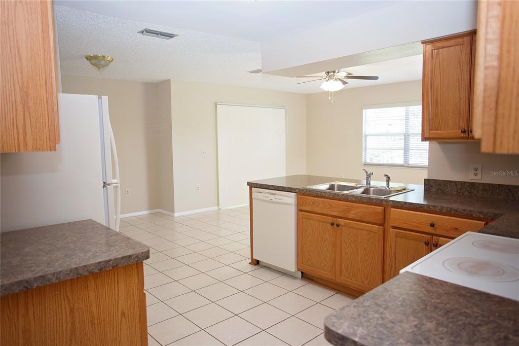 A kitchen with oak cabinets, laminate countertops, white appliances, and light-colored tile flooring — 10124 CARRIN ROAD, SPRING HILL, FL