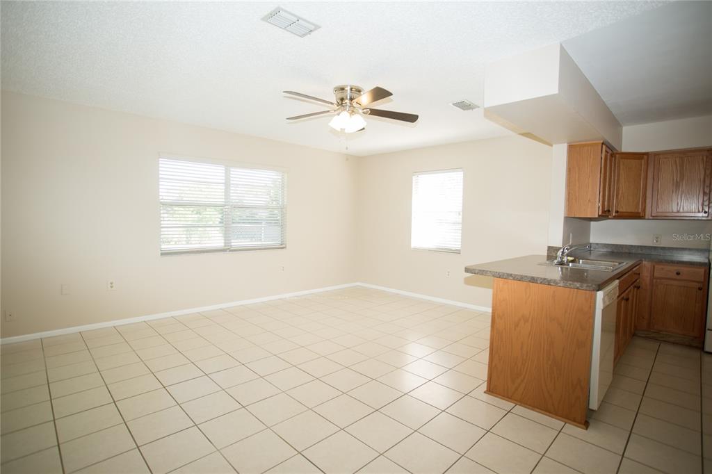 An open-concept kitchen and living area with beige tile floors and light-colored walls — 10124 CARRIN ROAD, SPRING HILL, FL