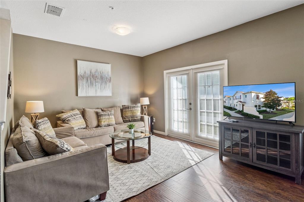 A living room features a beige sofa, glass coffee table, area rug, and television console — 3222 CUPID PLACE, KISSIMMEE, FL