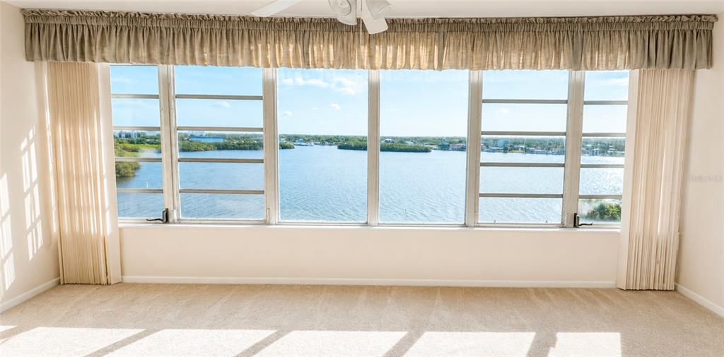 A carpeted room features a large window wall overlooking a body of water — 1847 SHORE DRIVE S UNIT 710, SOUTH PASADENA, FL