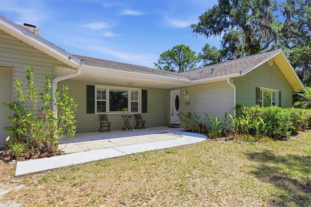 A light green house with a covered patio, white door, and a large front yard — 4420 GREENWOOD STABLES ROAD, SARASOTA, FL