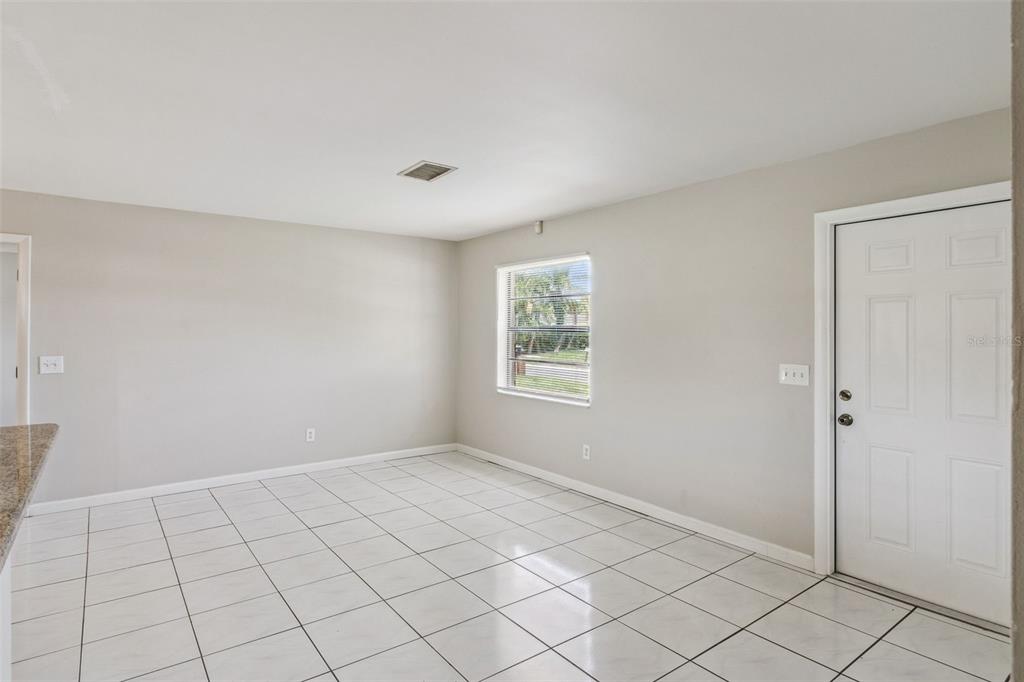 A bright room with white tiled floors, light gray walls, a window, and a door — 712 CLAYTON STREET, BRANDON, FL