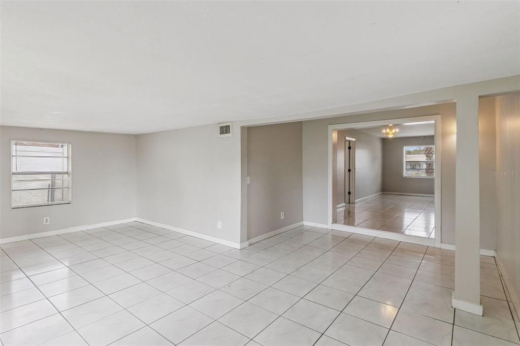 An interior view of a room with light-colored tile flooring and a large wall opening — 712 CLAYTON STREET, BRANDON, FL