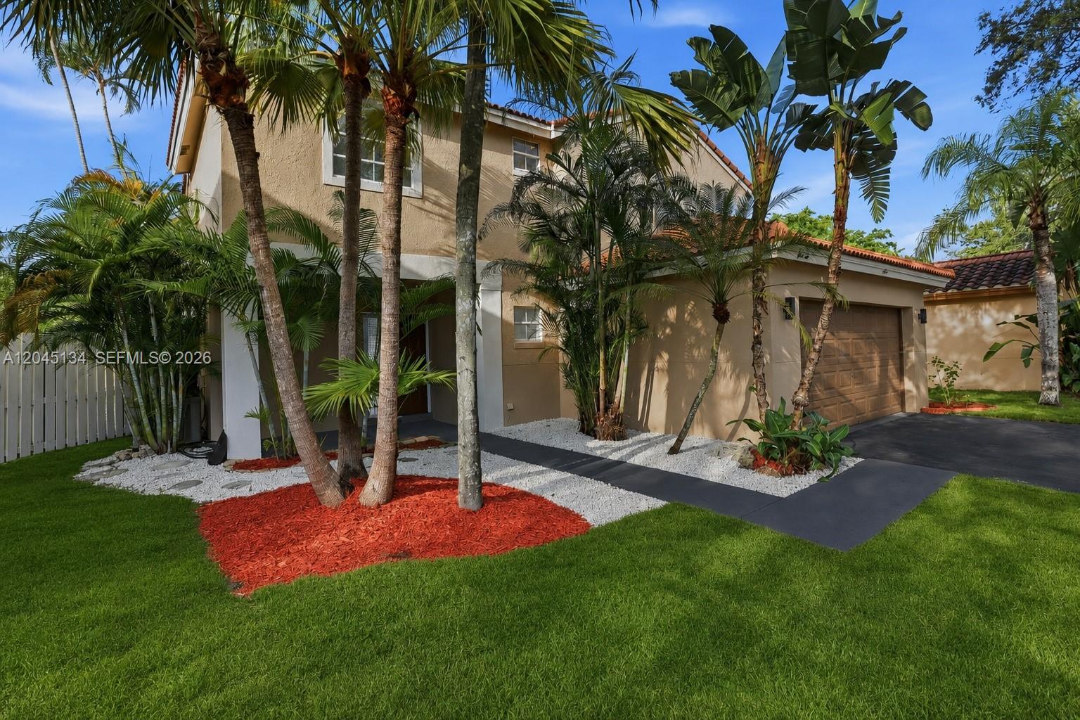 A two-story house with a tan stucco exterior, a garage, and palm trees in front — 13209 NW 12th Ct, Sunrise FL 33323, SUNRISE, FL