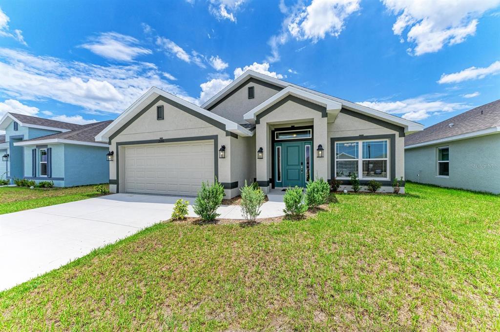 A single-story house with a beige stucco exterior, dark trim, and a teal front door — 2680 AVERLAND LOOP, NORTH PORT, FL