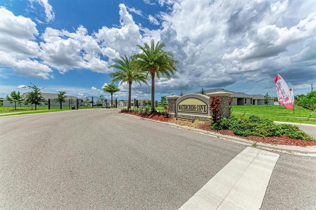 The entrance to Watercress Cove features a stone monument sign, palm trees, and gated access — 2680 AVERLAND LOOP, NORTH PORT, FL