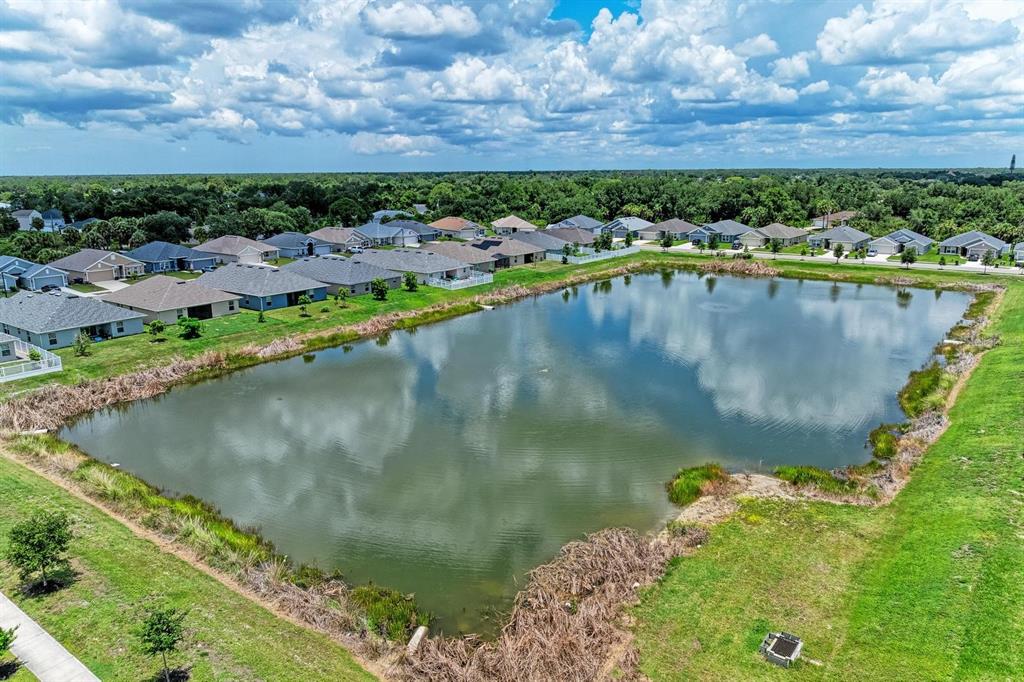 An aerial view shows a rectangular retention pond surrounded by suburban houses and green lawns — 2680 AVERLAND LOOP, NORTH PORT, FL
