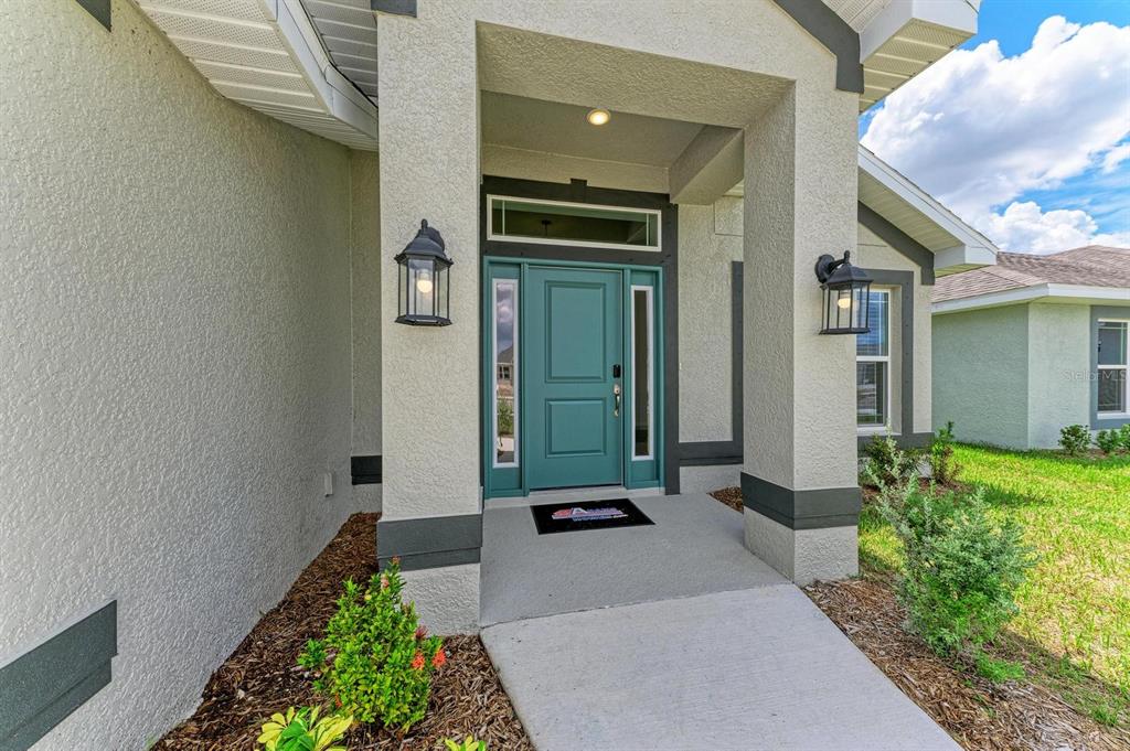 A teal front door with sidelights and a transom window sits under a covered entryway — 2680 AVERLAND LOOP, NORTH PORT, FL