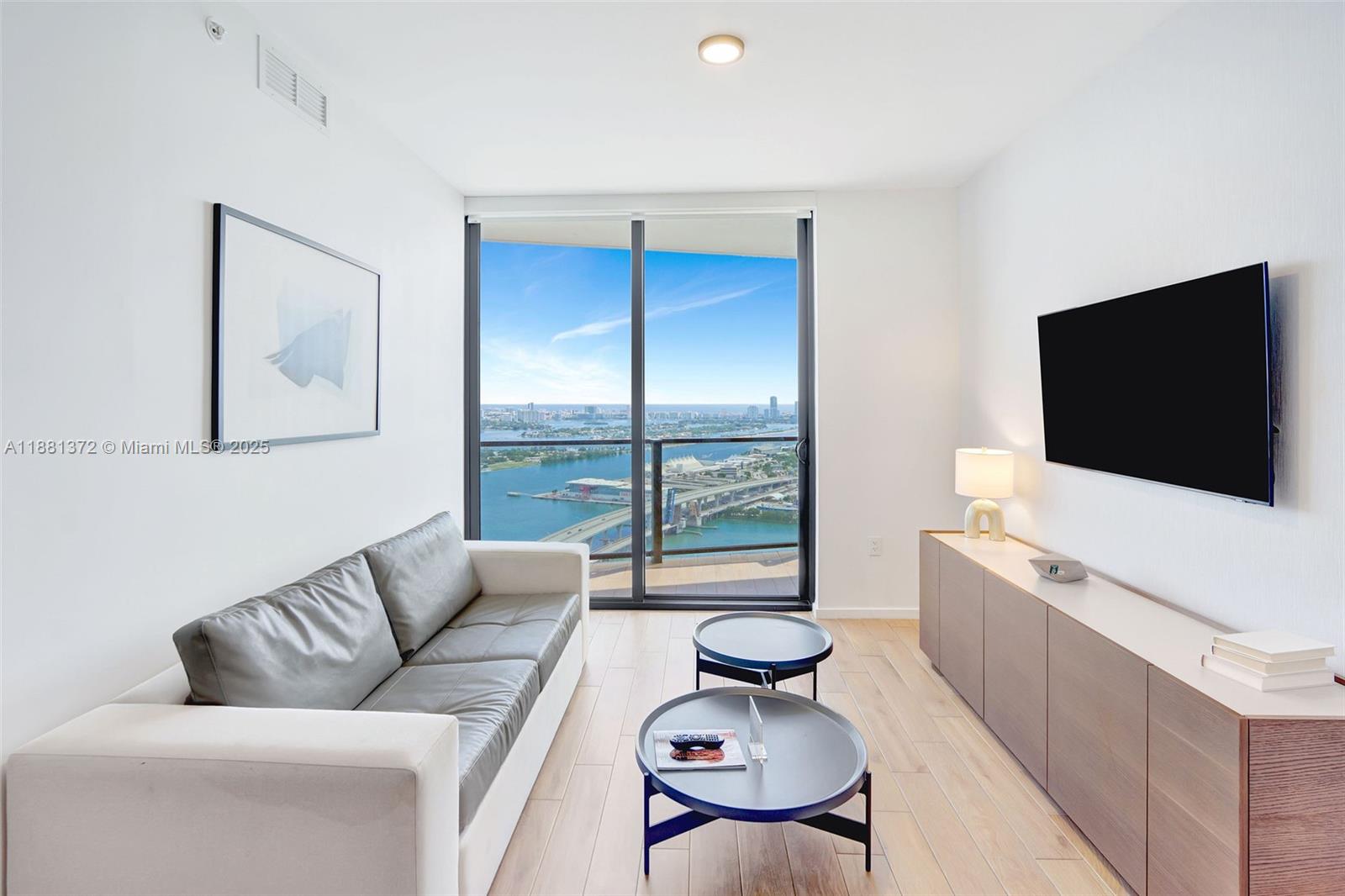 A living room features a gray sofa, two round coffee tables, and a water view — 398 NE 5th St # 3810, Miami FL 33132, MIAMI, FL