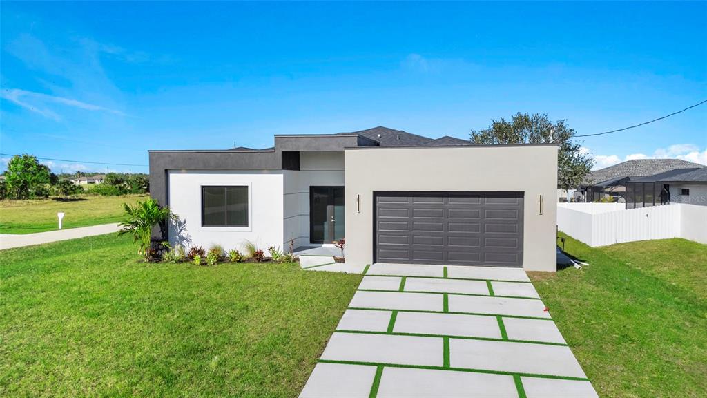 A concrete driveway leads toward a residential street with green lawns and palm trees — 2725 EMBERS PARKWAY W, CAPE CORAL, FL
